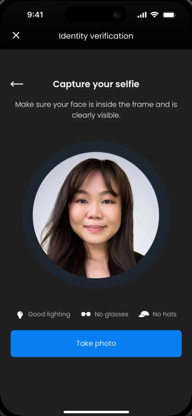 Identity verification screen asking you to capture your selfie, with a face inside a round frame, tips for good lighting, no glasses and no hats, and a Take photo button